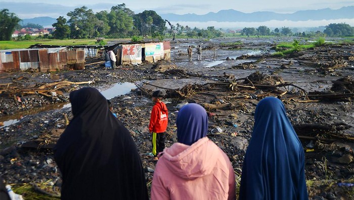 Warga berada di dekat puing-puing rumahnya yang dihanyutkan banjir lahar dingin di Nagari Bukik Batabuah, Agam, Sumatera Barat, Sabtu (6/4/2024). Data Nagari Bukik Batabuah menyebutkan banjir lahar dingin yang terjadi pada Jumat (5/4) itu menerjang 17 unit mobil dan sejumlah motor dan 40 rumah, tiga di antaranya rusak berat, serta areal pesawahan dan memutus sementara jalan alternatif mudik Pekanbaru - Padang.