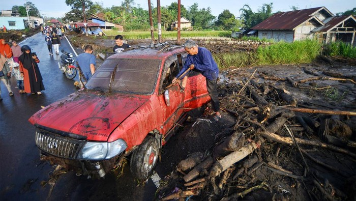 Warga membersihkan mobilnya yang terseret banjir lahar dingin di Nagari Bukik Batabuah, Agam, Sumatera Barat, Sabtu (6/4/2024). Data Nagari Bukik Batabuah menyebutkan  banjir lahar dingin  yang terjadi pada Jumat (5/4) itu menerjang 17 unit mobil dan sejumlah motor dan 40 rumah, tiga di antaranya rusak berat, serta areal pesawahan dan memutus sementara jalan alternatif mudik Pekanbaru - Padang.   ANTARA FOTO/Iggoy el Fitra/nz