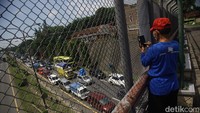 Warga menonton kemacetan kendaraan pemudik yang terjebak macet di KM 94 jalan tol Merak, Banten, Minggu (7/4/2024).