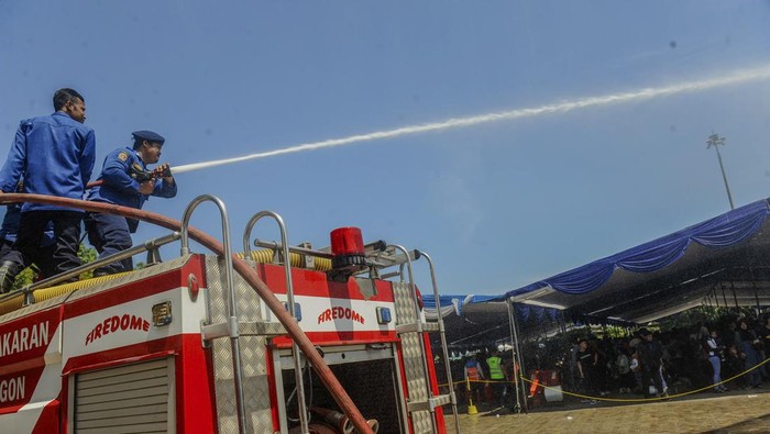 Petugas Pemadam Kebakaran menyemprotkan air ke jalanan di Pelabuhan Ciwandan, Kota Cilegon, Banten, Minggu (7/4/2024). Penyemprotan tersebut untuk mengurangi panas agar pemudik motor tidak kelelahan saat menunggu antrean penyeberangan. ANTARA FOTO/Muhammad Bagus Khoirunas/nym.