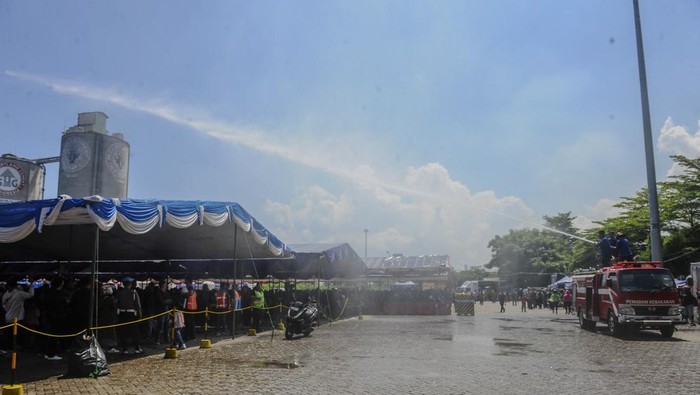 Petugas Pemadam Kebakaran menyemprotkan air ke jalanan di Pelabuhan Ciwandan, Kota Cilegon, Banten, Minggu (7/4/2024). Penyemprotan tersebut untuk mengurangi panas agar pemudik motor tidak kelelahan saat menunggu antrean penyeberangan. ANTARA FOTO/Muhammad Bagus Khoirunas/nym.