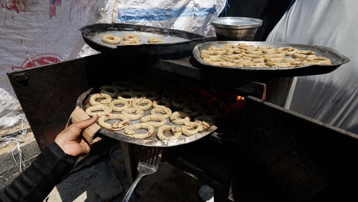 A displaced Palestinian family makes traditional cakes as they prepare for the Eid al-Fitr holiday which marks the end of the Muslim holy fasting month of Ramadan, amid the ongoing conflict between Israel and Hamas, at a tent camp in Rafah, in the southern Gaza Strip, April 8, 2024. REUTERS/Mohammed Salem