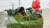 Peziarah sedang membersihakan makam kerabatnya di salah satu blok TPU Keputih Surabaya.