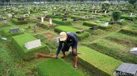 Seorang petugas makam sedang membersihakan makam di TPU Keputih Surabaya.