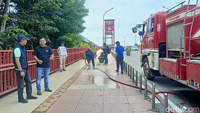 Petugas melakukan pembersihan di Jembatan Ampera untuk lokasi salat id