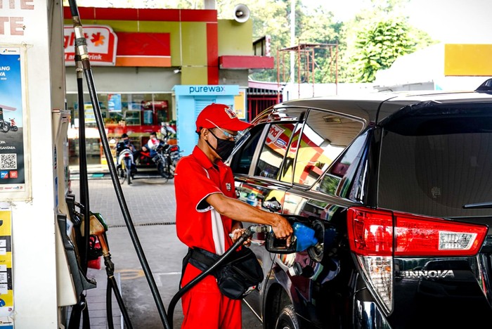 Petugas SPBU sedang mengisi BBM di salah satu mobil pelanggan.
