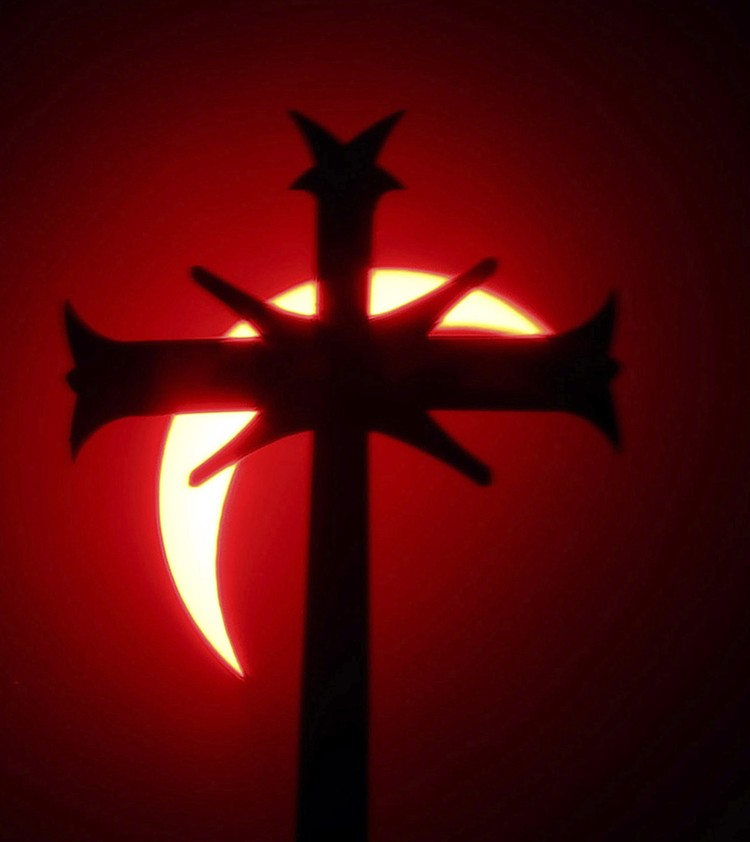 A cross on top of a steeple of the St. Johns the Evangelist Church in Attleboro, Mass. partially covers the sun during a total solar eclipse Monday, April 8, 2024. (Mark Stockwell/The Sun Chronicle via AP)