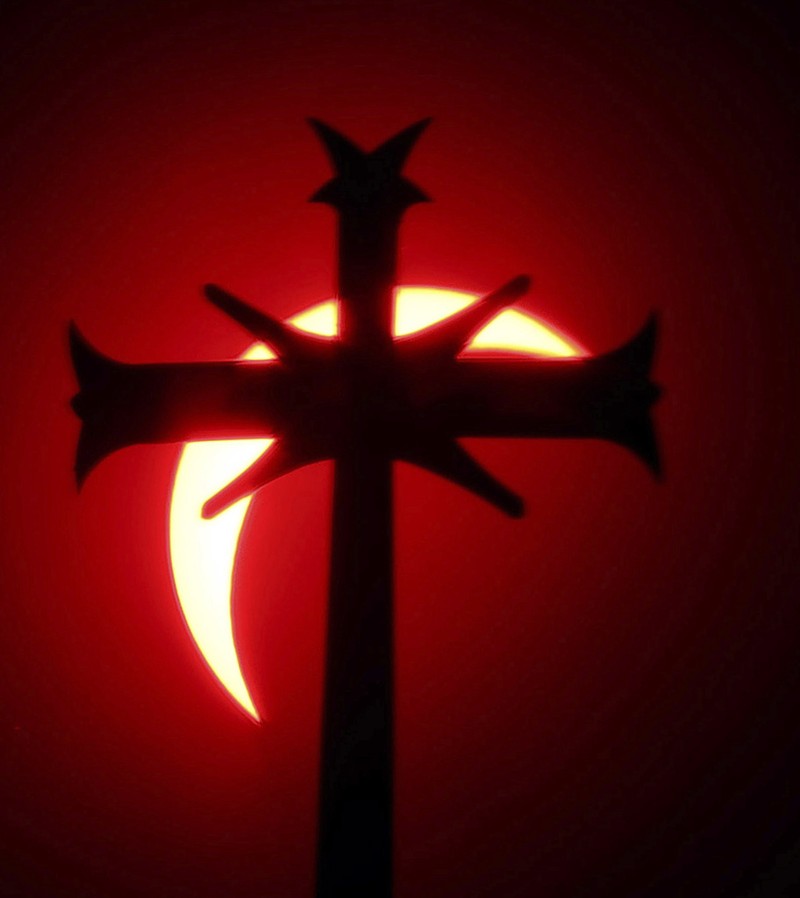 A cross on top of a steeple of the St. John's the Evangelist Church in Attleboro, Mass. partially covers the sun during a total solar eclipse Monday, April 8, 2024. (Mark Stockwell/The Sun Chronicle via AP)