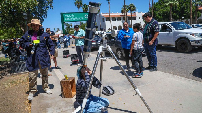 Potret Siswa-Mahasiswa Meksiko & AS Amati Gerhana Matahari Total HERMOSILLO, MEXICO - APRIL 8: Students from the Astrobiology club explain the phenomenon of the eclipse in the solar system at the student plaza of the University of Sonora on April 8, 2024 in Hermosillo, Mexico. Millions of people have flocked to areas across North America that are in the path of totality in order to experience a total solar eclipse. During the event, the moon will pass in between the sun and the Earth, appearing to block the sun. (Photo by Luis Gutierrez/Norte Photo/Getty Images)