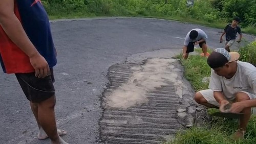 Sejumlah warga bergotong royong dengan mengeluarkan iuran dana pribadi untuk menambal jalan berlubang di Nusa Penida, Kabupaten Klungkung, Bali, Senin (8/4/2024). (Foto: Dok. Putu Gde Suka Widana)