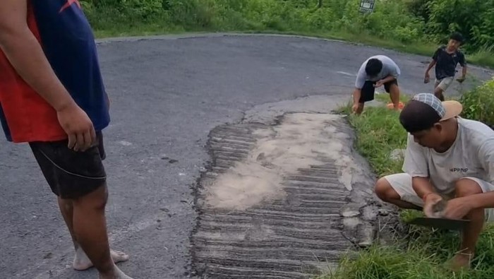Sejumlah warga bergotong royong dengan mengeluarkan iuran dana pribadi untuk menambal jalan berlubang di Nusa Penida, Kabupaten Klungkung, Bali, Senin (8/4/2024). (Foto: Dok. Putu Gde Suka Widana)