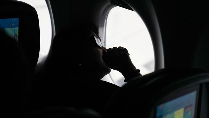 A passenger wears solar eclipse glasses as she looks from a special Delta Airlines eclipse flight over the skies of the U.S., April 8, 2024. REUTERS/Leonardo Benassatto