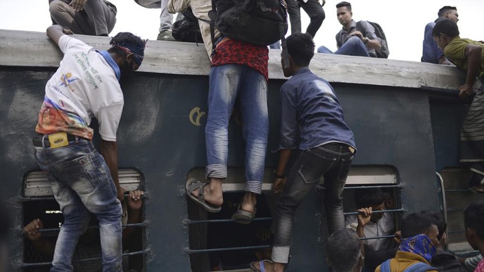 Bangladeshi Muslims maneuver their way on the roof of an overcrowded train to travel home for Eid al-Fitr celebrations, at a railway station in Dhaka, Bangladesh, Tuesday, April 9, 2024. Hundreds of thousands of people working in Dhaka are leaving for their hometowns to celebrate the upcoming Eid al-Fitr with their families. (AP Photo/Mahmud Hossain Opu)