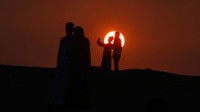 Warga berfoto dengan latar belakang matahari terbit sebelum pelaksanaan salat.