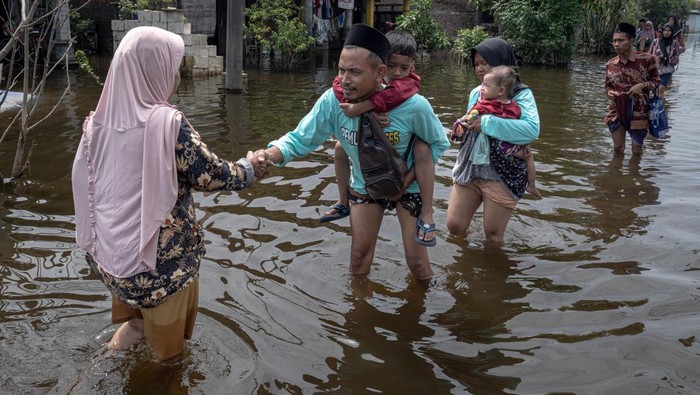 Warga melewati jalan desa yang terendam banjir untuk merayakan Lebaran bersama keluarga di Desa Sayung, Kecamatan Sayung, Kabupaten Demak, Jawa Tengah, Rabu (10/4/2024).  Banjir yang merendam desa setempat selama 28 hari sejak Rabu (13/3) akibat luapan Sungai Dombo-Sayung yang tak mampu menampung debit aliran air karena curah hujan tinggi itu belum surut dengan ketinggian banjir bervariasi hingga mencapai 70 sentimeter, sehingga mengganggu aktivitas serta mobilitas warga dalam merayakan Hari Raya Idul Fitri 1 Syawal 1445 H. Warga berharap kepada Pemkab Demak agar menambah jumlah pompa air yang beroperasi agar banjir cepat surut. ANTARA FOTO/Aji Styawan/foc.