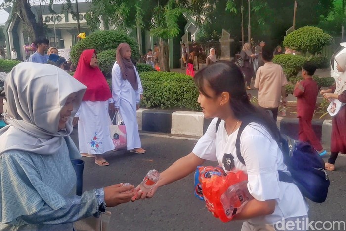 Warga memberikan air minum kepada jemaah Salat Id di Karawang.