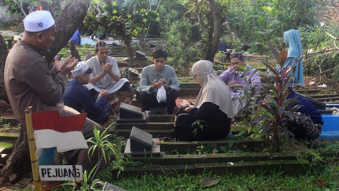 Warga berdoa di pusara keluarga saat berziarah di tempat pemakaman umum (TPU) Kebayoran Lama, Jakarta, Kamis (11/4/2024). Berziarah ke makam kerabat saudara pada hari kedua lebaran tersebut menjadi tradisi warga asli Jakarta saat Idul Fitri untuk mendoakan keluarganya yang telah meninggal. ANTARA FOTO/Muhammad Iqbal/nym.