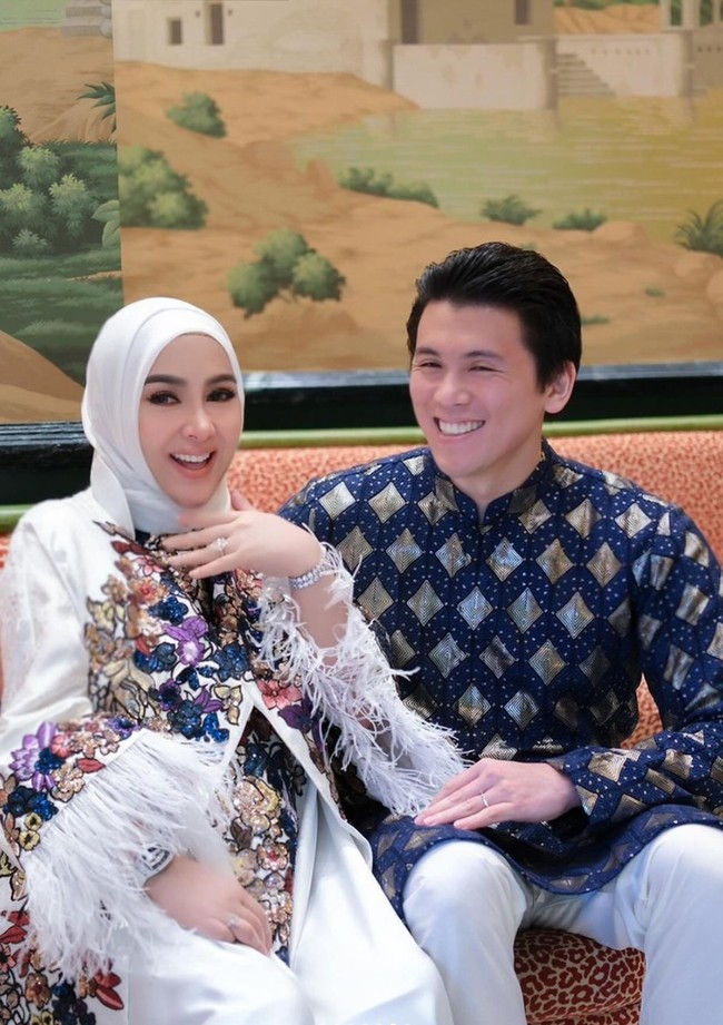 Selalu stylish seperti biasa, Syahrini tampil mengenakan dress panjang berwarna putih. Dress tersebut dipercantik dengan motif bunga warna-warni pada bagian tengahnya dan rubai-rumbai pada bagian lengannya. Sementara sang suami mengenakan baju kurta bermotif warna biru tua dipadukan celana panjang putih. Foto: Instagram/@princessyahrini