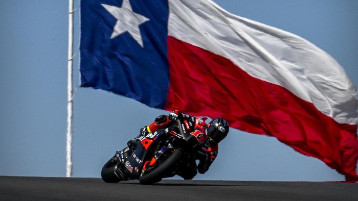 Apr 12, 2024; Austin, TX, USA; Maverick Vinales (12) of Spain and Aprilia Racing rides past the flag of Texas during practice for the MotoGP Grand Prix of the Americas at Circuit of The Americas. Mandatory Credit: Jerome Miron-USA TODAY Sports