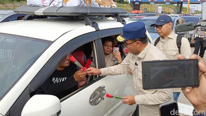Menhub Budi Karya Sumadi memberikan bunga ke pemudik arus balik di Tol Kalikangkung, Sabtu (13/4/2024).