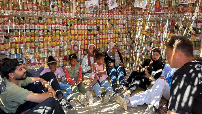 Palestinians sit inside a tent made out of canned food containers to illustrate the situation of Palestinians amid the ongoing conflict between Israel and the Palestinian Islamist group Hamas, and to launch a mutual help initiative, at Deir Al-Balah in the central Gaza Strip, April 6, 2024. REUTERS/Doaa Rouqa