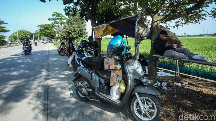 Sejenak Melepas Lelah di Depan Hamparan Sawah Karawang Sejumlah warga beristirahat di jalan Lingkar Tanjungpura, Karawang, Sabtu (13/4/2024).