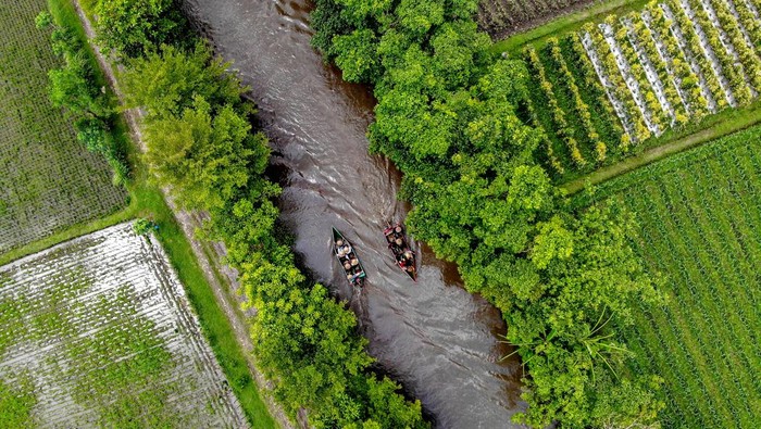 Foto udara sejumlah pengunjung menaiki perahu di Wisata Tani Betet, Ngronggot, Nganjuk, Jawa Timur, Sabtu (13/4/2024). Kunjungan wisata di saluran irigasi persawahan yang dikelola warga setempat menjadi obyek wisata itu meningkat dari hari biasanya yakni sekitar 100 per hari menjadi sekitar 500 pengunjung per hari saat libur Lebaran.  ANTARA FOTO/Muhammad Mada/nz