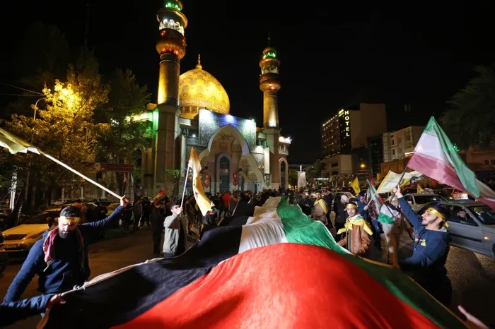 Demonstrasi di Tehran dukung serangan Iran ke Israel. Pria mengangkat replika peluru misil (Vahid Salemi/AP). Pembentangan bendera Palestina raksasa (Atta Kenare/AFP).