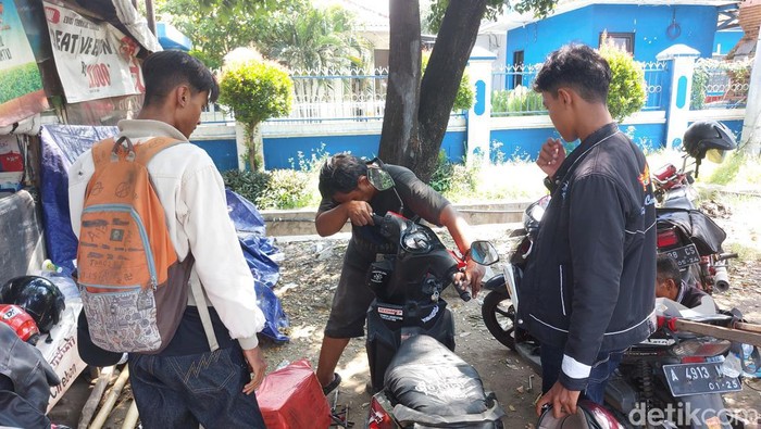 Drajat (43) (memegang stang motor) saat memperbaiki kendaraan milik pemudik di jalur arteri pantura Cirebon.