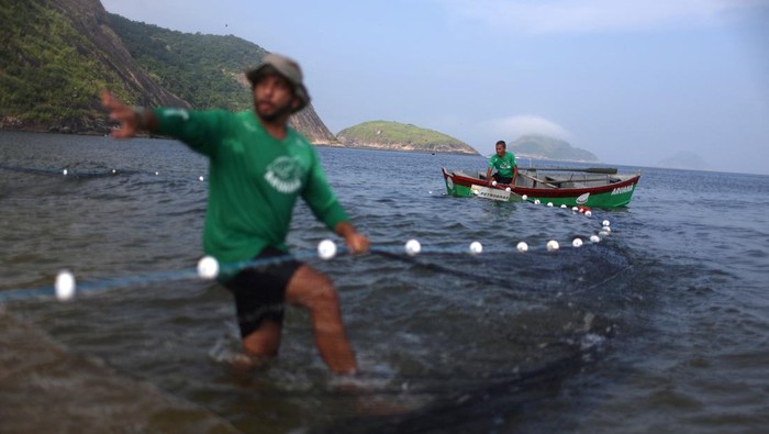Aksi Merawat Penyu Tingkatkan Kesadaran Peduli Lingkungan Biologist Larissa Araujo, 35, of the Aruana Project, a project focused on research and conservation, covers a Green Sea Turtle during the intentional capture to monitor turtles' health, weight and pollution level, in Itaipu beach in Niteroi, Brazil April 11, 2024. REUTERS/Pilar Olivares