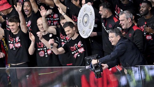 Leverkusens head coach Xabi Alonso, center, holds the championship trophy as he celebrates with players winning the German Bundesliga after the match against Werder Bremen at the BayArena in Leverkusen, Germany, Sunday, April 14, 2024. (David Inderlied/dpa via AP)