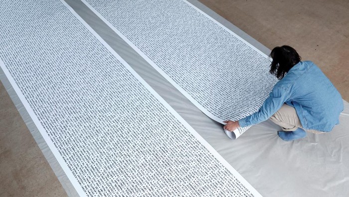 French artist Baptiste Chebassier poses in the middle of a part of his artwork, made from rolls of recycled paper on which names of 30,249 Olympic medallists will be written, at the Chebassier workshop in Saint-Ouen, near Paris, France, April 5, 2024. REUTERS/Noemie Olive