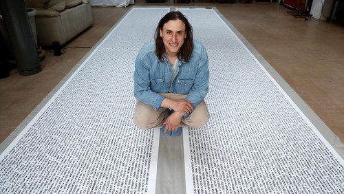 French artist Baptiste Chebassier poses in the middle of a part of his artwork, made from rolls of recycled paper on which names of 30,249 Olympic medallists will be written, at the Chebassier workshop in Saint-Ouen, near Paris, France, April 5, 2024. REUTERS/Noemie Olive