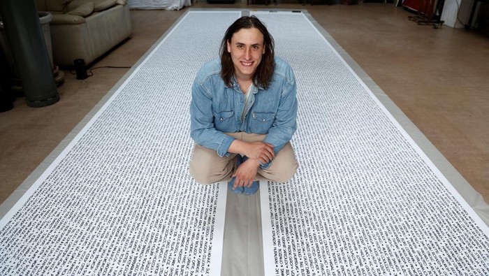 French artist Baptiste Chebassier poses in the middle of a part of his artwork, made from rolls of recycled paper on which names of 30,249 Olympic medallists will be written, at the Chebassier workshop in Saint-Ouen, near Paris, France, April 5, 2024. REUTERS/Noemie Olive