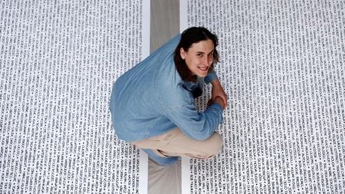 French artist Baptiste Chebassier poses in the middle of a part of his artwork, made from rolls of recycled paper on which names of 30,249 Olympic medallists will be written, at the Chebassier workshop in Saint-Ouen, near Paris, France, April 5, 2024. REUTERS/Noemie Olive