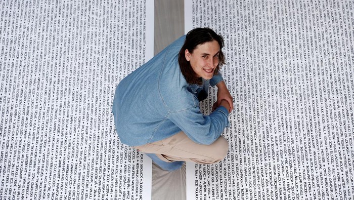 French artist Baptiste Chebassier poses in the middle of a part of his artwork, made from rolls of recycled paper on which names of 30,249 Olympic medallists will be written, at the Chebassier workshop in Saint-Ouen, near Paris, France, April 5, 2024. REUTERS/Noemie Olive