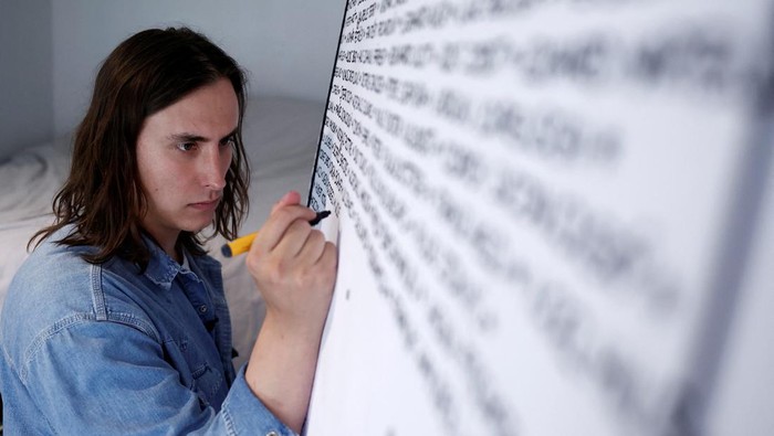 French artist Baptiste Chebassier poses in the middle of a part of his artwork, made from rolls of recycled paper on which names of 30,249 Olympic medallists will be written, at the Chebassier workshop in Saint-Ouen, near Paris, France, April 5, 2024. REUTERS/Noemie Olive