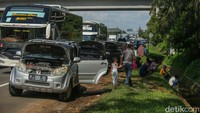 Padatnya arus lalu lintas menuju Gerbang Tol Cikampek Utama membuat para pemudik menepi di bahu jalan. Beberapa dari mereka nampak membuka kap mesin mobil.