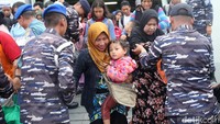 Prajurit TNI AL membantu warga turun dari kapal.