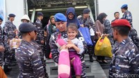 Seorang prajurit menggendong bayi turun dari kapal.