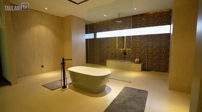 Didominasi warna putih dengan sentuhan kayu, kamar mandi bak di resor mewah lengkap dengan bathtub dan area shower dengan pancuran hujan. (Foto: YouTube/Taulany TV)