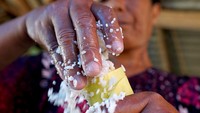 Seorang warga memasukan beras ketan ke dalam bambu untuk dimasak menjadi nasi bulu atau lemang di Desa Huidu, Kabupaten Gorontalo, Gorontalo, Selasa (16/4/2024).
