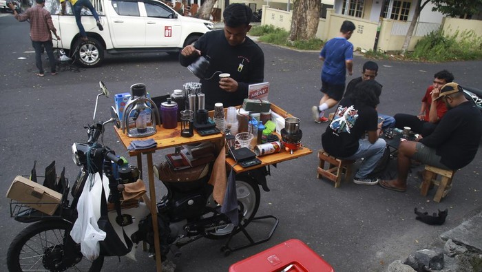 Modifikasi motor klasik jadi warung kopi keliling Barista Kopi Godahang menyeduh kopi saat berjualan di sekitar Stadion Gelora Kie Raha Ternate, Maluku Utara, Selasa (16/4/2024). Asmar memodifikasi motor klasik Honda C70 miliknya menjadi warung kopi keliling yang mejualΒ berbagai macamΒ kopi ala cafe, dengan harga terjangkau mulai dari Rp15 ribu - Rp18 ribu, meskipun sederhana warung ini cukup diminati kalangan remaja. ANTARA FOTO/Andri Saputra/Spt.