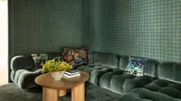 Rumah minimalis juga bisa memainkan warna-warna yang lebih gelap atau cerah. Ruang tamu ini memakai warna hijau tua dengan bahan furnitur yang mirip yakni beludru yang lembut, berkilau meskipun warnanya gelap pada sofa, dinding, hingga karpetnya.  Foto: Studio DB via Livingetc