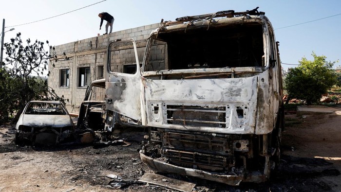 Sisa-sisa Serangan Brutal Pemukim Israel di Tepi Barat A Palestinian man sits near a damaged house and damaged cars after Israeli settlers attacked the village of al-Mughayyer, in the Israeli-occupied West Bank, April 13, 2024. REUTERS/Mohammed Torokman
