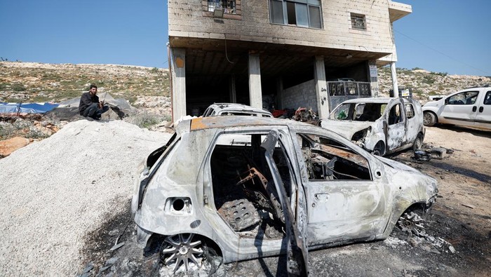 Sisa-sisa Serangan Brutal Pemukim Israel di Tepi Barat A Palestinian man sits near a damaged house and damaged cars after Israeli settlers attacked the village of al-Mughayyer, in the Israeli-occupied West Bank, April 13, 2024. REUTERS/Mohammed Torokman