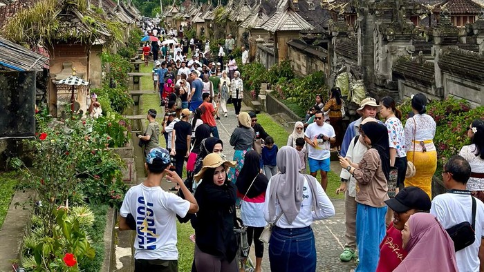 Pelancong pelesiran di Desa Wisata Penglipuran, Bangli, Bali, saat libur Lebaran 2024. Desa itu sampai dikunjungi 7 ribu turis per hari.
