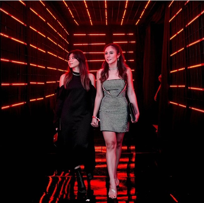 Pada sebuah acara, Wulan Guritno dan Shalom Razade tampil elegan. Shalom terlihat anggun dengan sleeve dress cutout hitam yang dipadukan boot senada. Sementara itu, ibunya mengengakan minidress sequin dengan sepatu heels. Foto: dok. Instagram @wulanguritno