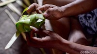 Penjual tengah merangkai janur untuk wadah ketupat di Pasar Kembang, Surabaya.
