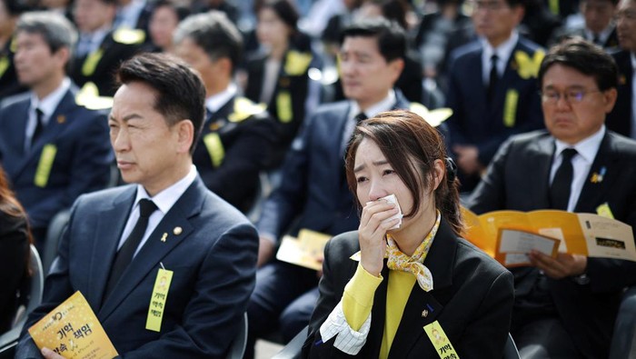 People pay their silent tributes behind a large yellow colored ribbon dedicated to victims of the sunken Sewol ferry disaster that killed 304 people, mostly school students, during a ceremony to commemorate its tenth anniversary in Ansan, South Korea, April 16, 2024. REUTERS/Kim Hong-Ji
